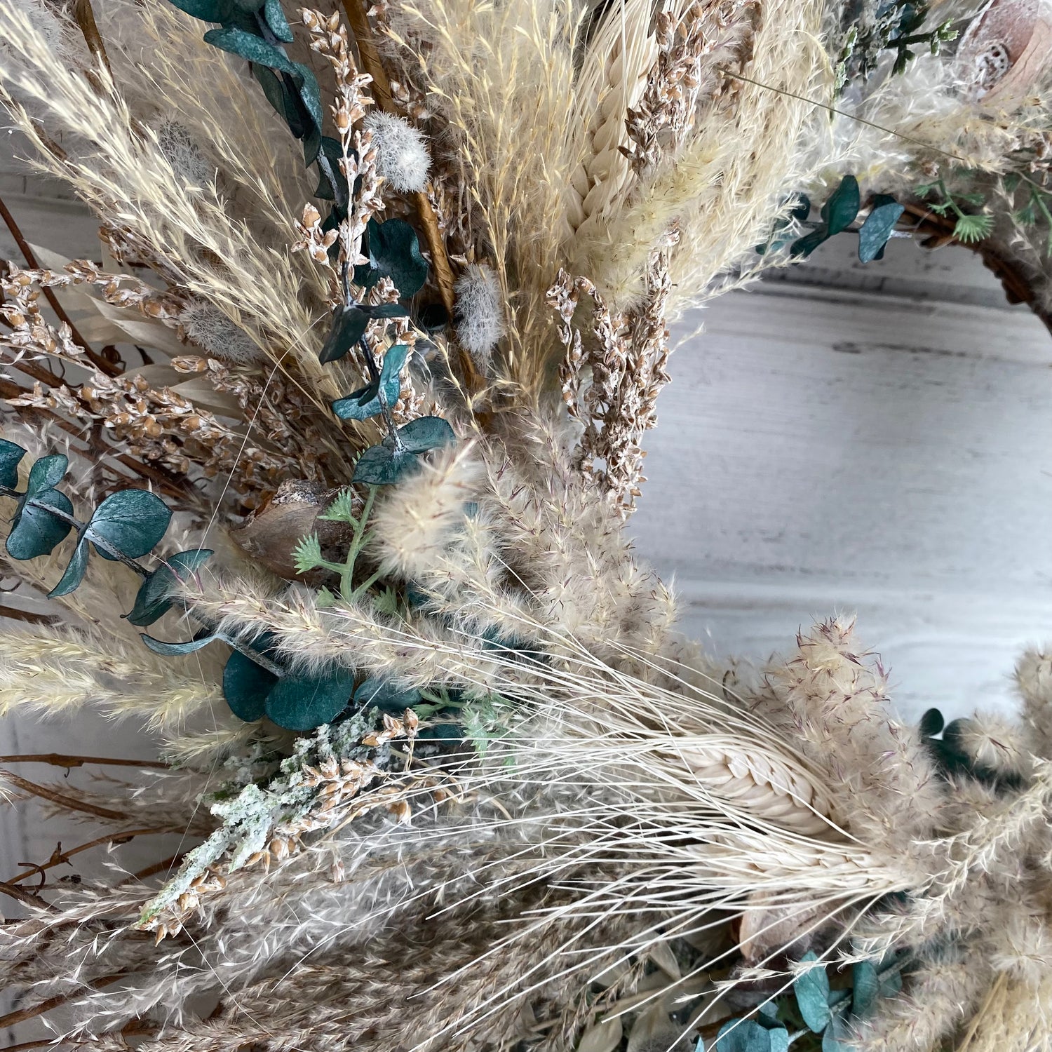 a wreath with creme and neutral cotton stems, pampas grass, eucalyptus, and other dried grasses.