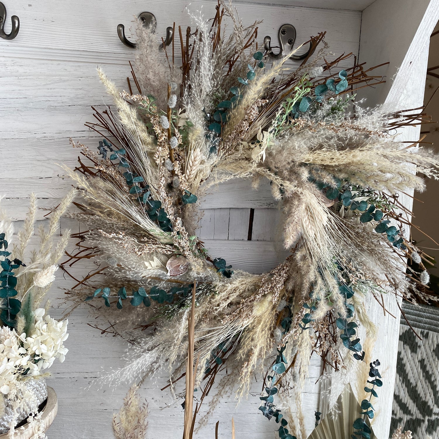 a wreath with creme and neutral cotton stems, pampas grass, eucalyptus, and other dried grasses.